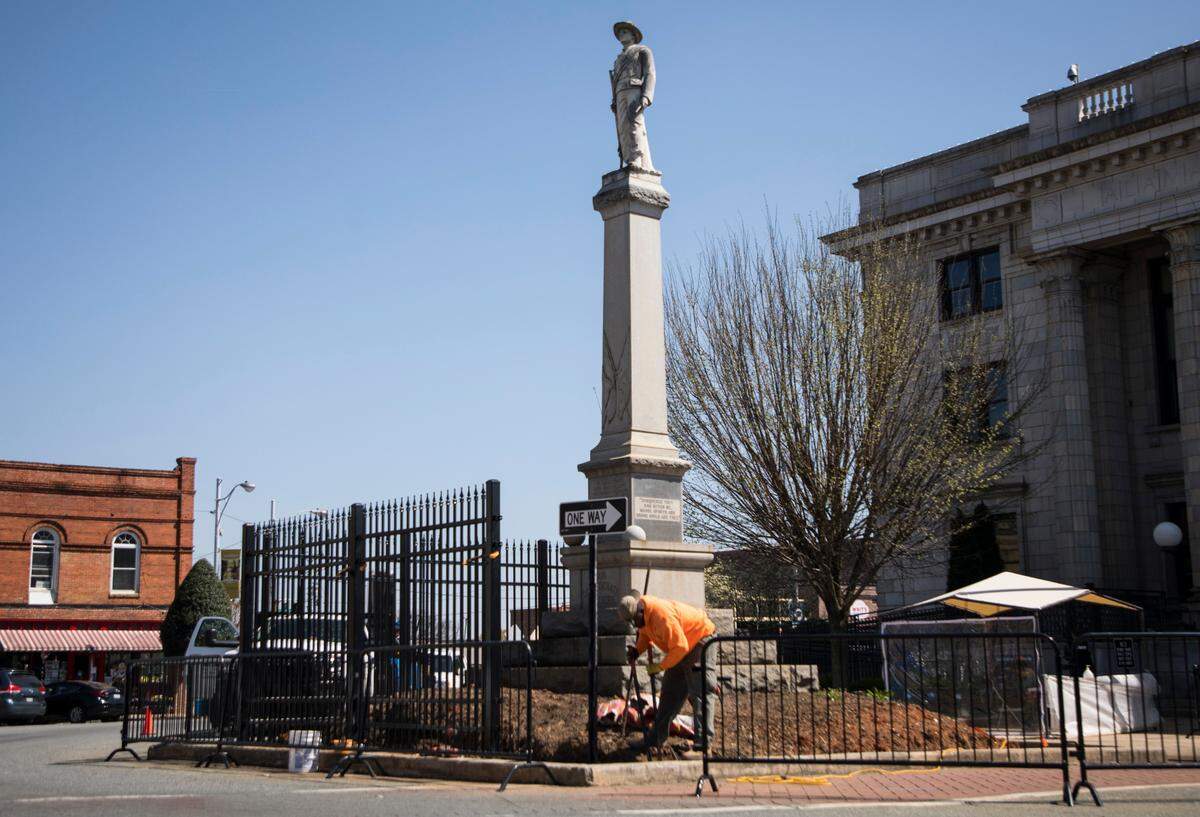 Workers install an 8-foot-tall permanent fence around the Confederate monument in downtown Graham on April 5, 2021.