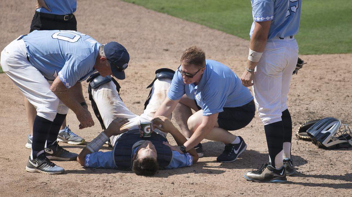 North Carolina coach Mike Fox and trainer Terri Jo Rucinski attend to catcher Cody Roberts after he was hit by a foul ball in the seventh inning against Duke last Sunday.