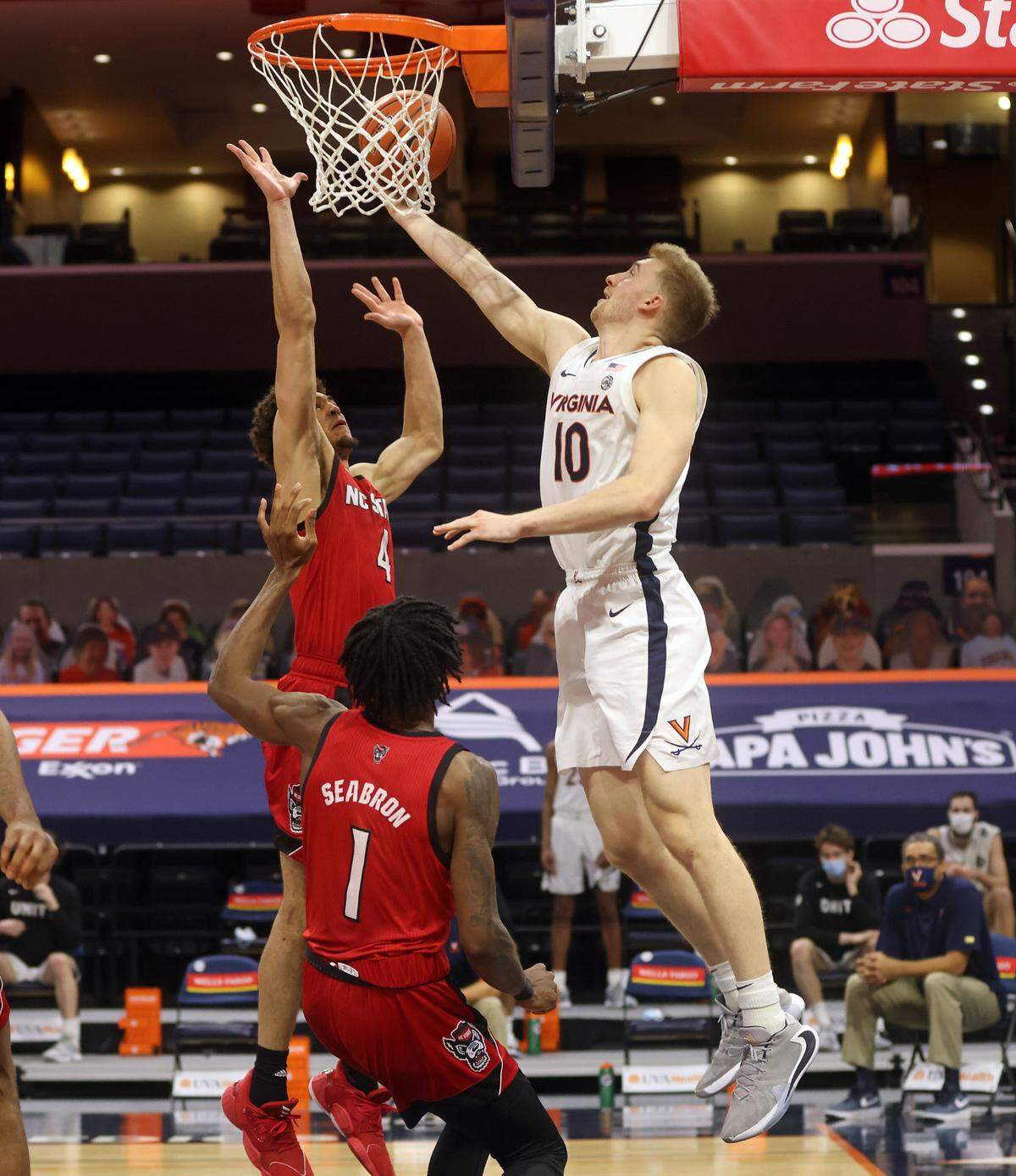Virginia forward Sam Hauser (10) shoots under pressure from North Carolina State forward Jericole Hellems (4)and North Carolina State guard Dereon Seabron (1) during the game Wednesday in Charlottesville, Va. North Carolina State defeated Virginia 68-61.
