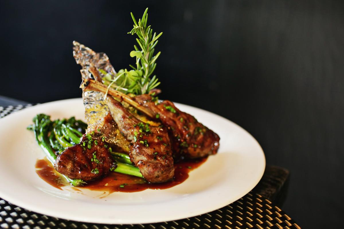 The Genghis Khan lamb chops are redolent of Chinese spices, served atop a mound of sweet onion curry risotto and broccolini, and garnished with a lacy crown of spun sugar. at Fusion Fish in Chapel Hill.