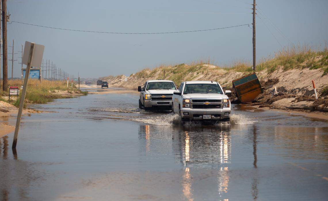 Trucks drive through standing water on N.C. 12 near Hatteras Village Sunday, Sept. 8, 2019 in the aftermath of Hurricane Dorian.