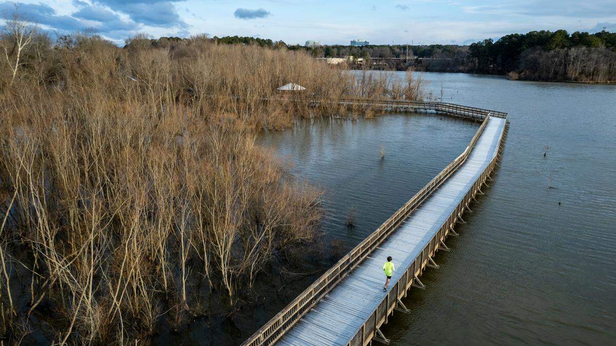 Zachary Bugg runs along Crabtree Creek Trail in Raleigh after a light dusting of snow accumulated on the boardwalk structures on the trail Saturday morning, Jan. 29, 2022.