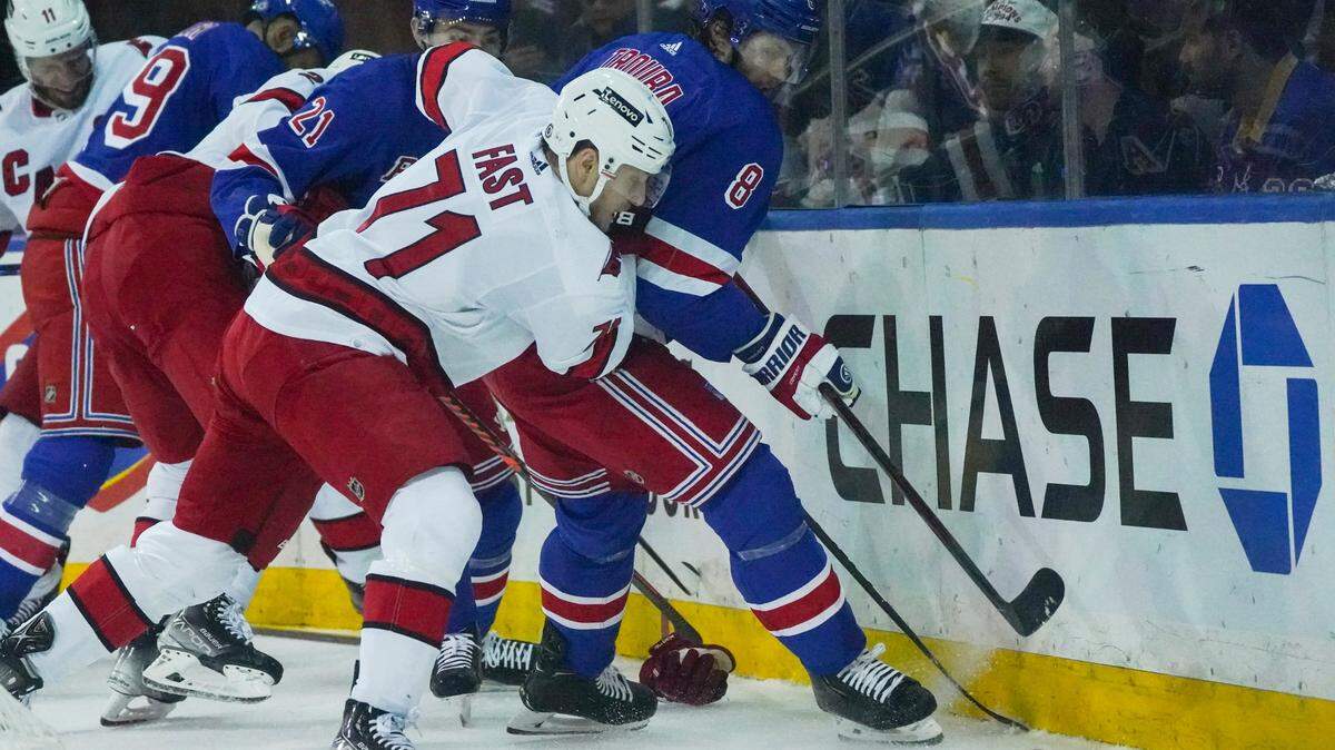 Carolina Hurricanes right wing Jesper Fast (71) and New York Rangers defenseman Jacob Trouba (8) goes for a loose puck during first period of an NHL hockey game, Tuesday, April 12, 2022, in New York. (AP Photo/Bebeto Matthews)