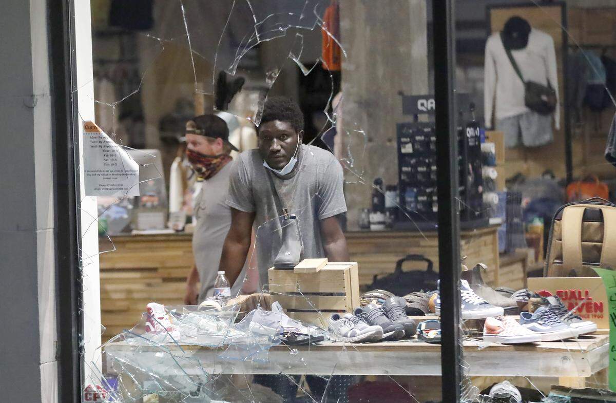 An employee stands in Apex Outfitter and Board Company to help protect the shop during a protest in downtown Raleigh, N.C. Saturday, May 30, 2020.