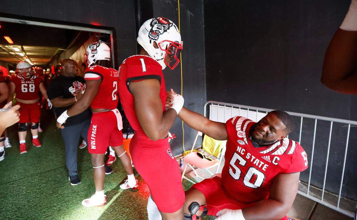 N.C. State linebacker Isaiah Moore (1) greets center Grant Gibson (50) before they head out onto the field to warmup before N.C. State’s game against Boston College at Carter-Finley Stadium in Raleigh, N.C., Saturday, Nov. 12, 2022.