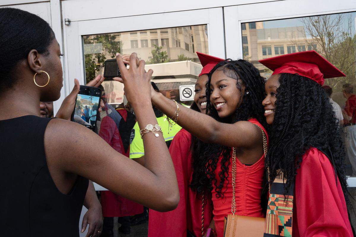 15-year-old Rebecca Malonda takes a selfie with her older cousins, Grace and Gloria Lelo, after they graduated from Middle Creek High School on Wednesday, June 18, 2025 at the Raleigh Convention Center.