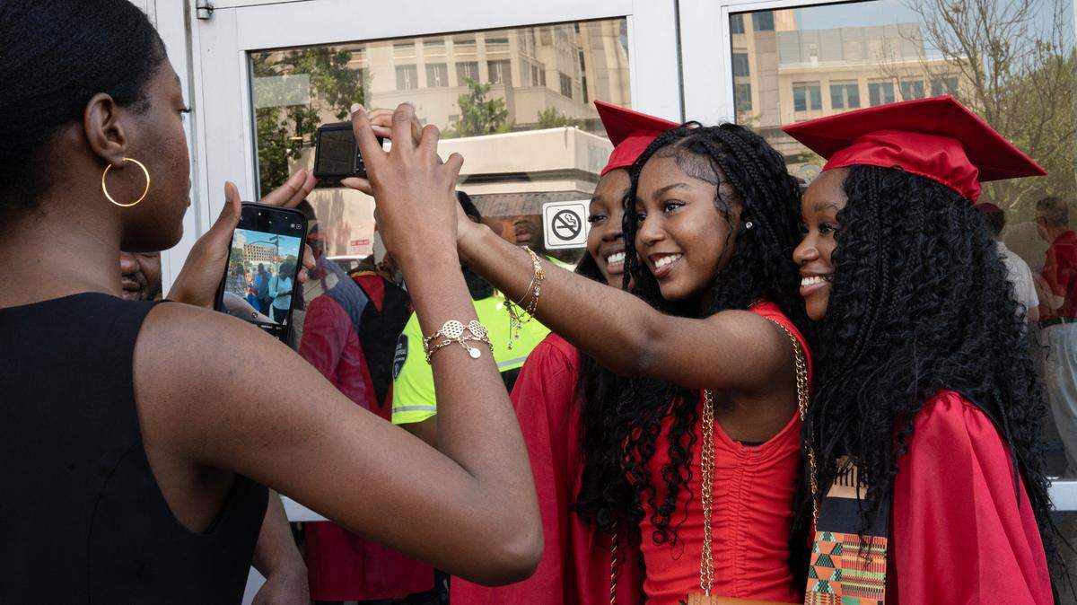 15-year-old Rebecca Malonda takes a selfie with her older cousins, Grace and Gloria Lelo, after they graduated from Middle Creek High School on  June 18, 2025, at the Raleigh Convention Center. This year’s graduation season for Wake County schools kicks off on May 21.