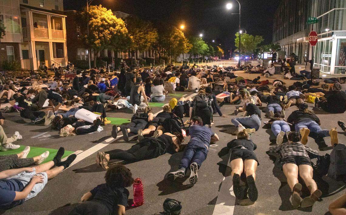 Protesters lie down in the street outside the Durham Police Department headquarters to hold a moment of silence for nine minutes, to represent the time a Minneapolis police officer knelt on the neck of George Floyd resulting in his death, before the action was interrupted by a car barreling toward them but stopped feet short of injuring anyone, on Wednesday, Jun. 4, 2020, in Durham, N.C.