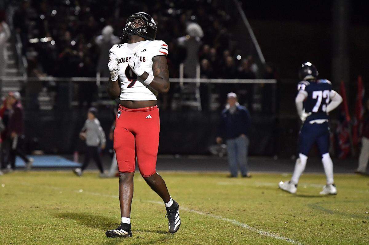 Apex Friendship offensive lineman Nolan Bennett (73) walks off the field while Rolesville defensive lineman Zavion Griffin-Haynes (9) celebrates their victory in overtime. The Apex Friendship Patriots and the Rolesville Rams met in the second round of the NCHSAA 8A Playoff game in Apex, N.C. on November 14, 2025. Rolesville wins 14-7 in overtime.