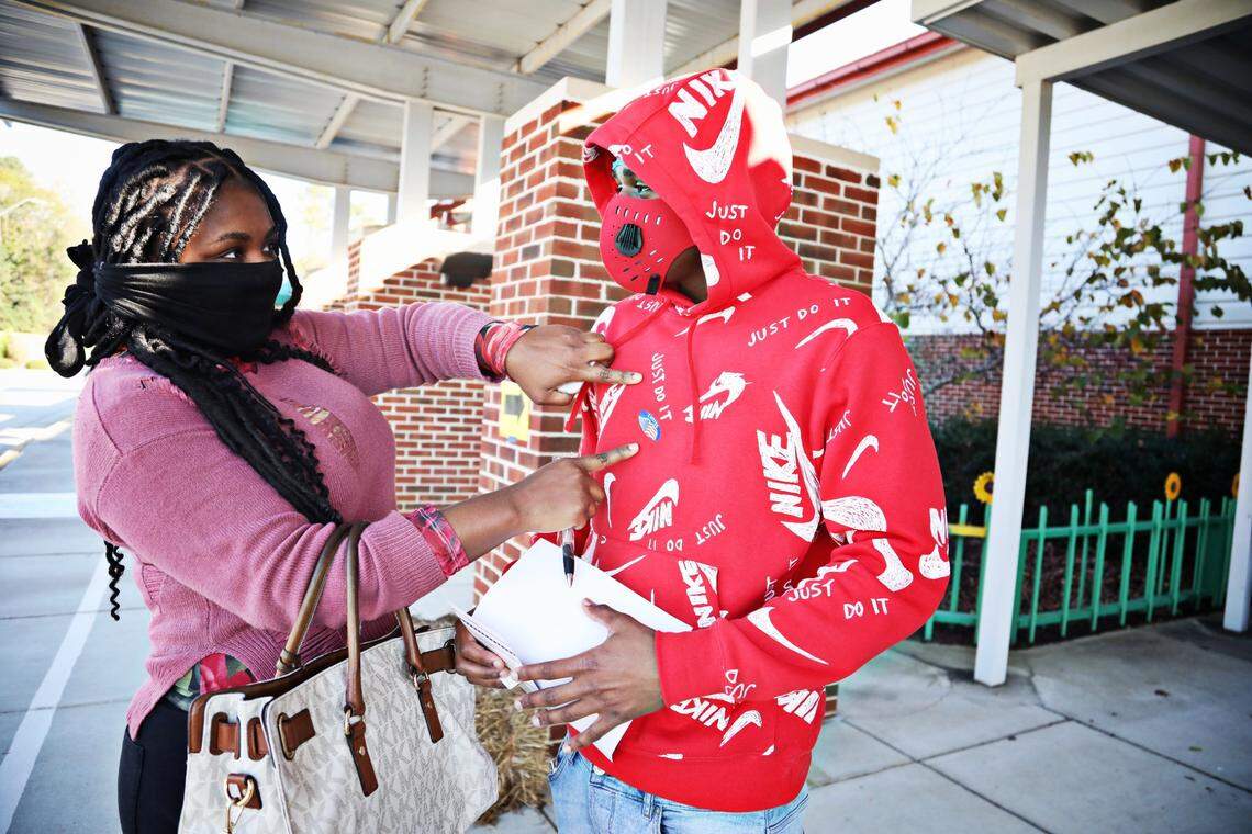 Crystal Owens, left, makes sure her son, Rayshaun Bartee, 19, puts on his sticker after voting for the first time at Banks Road Elementary in Fuquay-Varina on Tuesday morning, Nov. 3, 2020. When asked what it was like to vote for the first time, Bartee says, “it was a lot of pressure.”