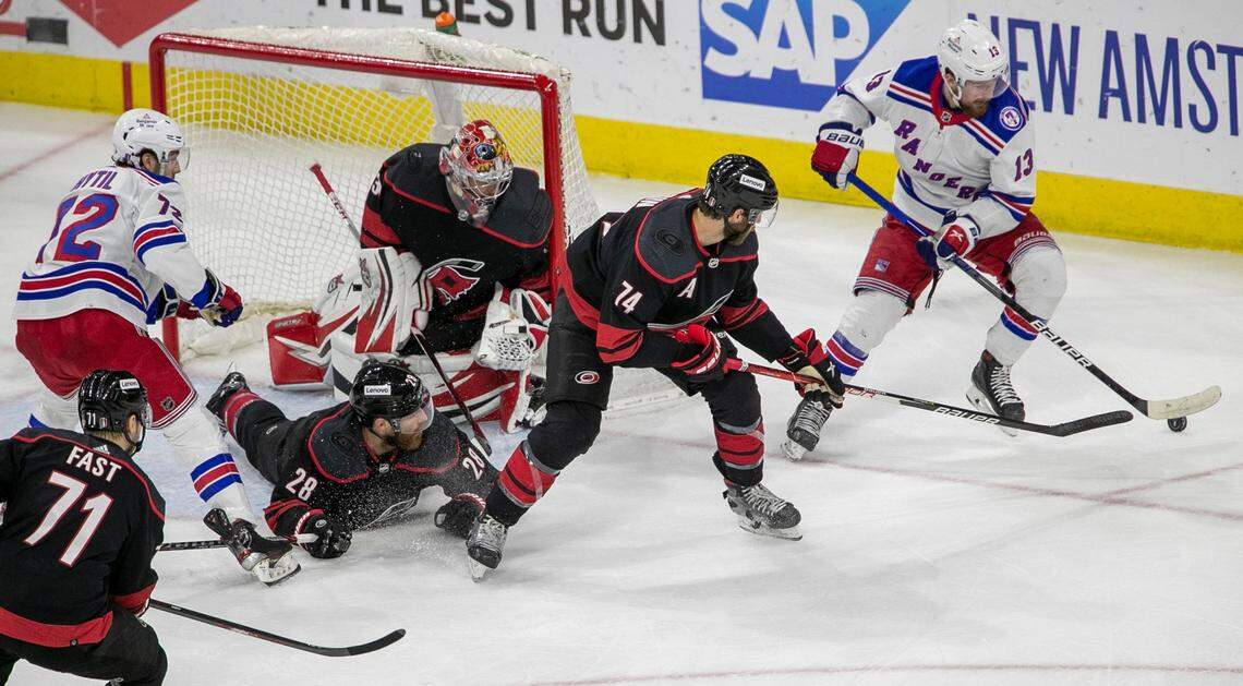 New York Rangers Alexis Lafreniere (13) moves the puck as Carolina Hurricanes Jaccob Slavin (74) and Ian Cole (28) assist goalie Antii Raanta (32) on defense in the first period on Friday, May 20, 2022 during game two of the Stanley Cup second round at PNC Arena in Raleigh, N.C.