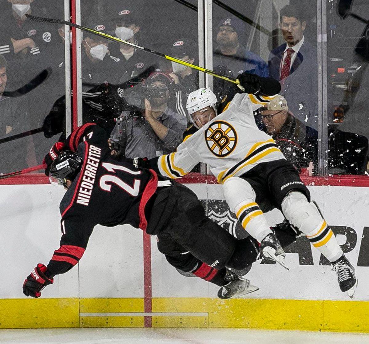 Carolina Hurricanes’ Nino Niederreiter (21) checks Boston’s Charlie McAvoy (73) into the boards during the second period on Monday, May 2, 2022 during game one of their Stanley Cup first round series at PNC Arena in Raleigh, N.C.