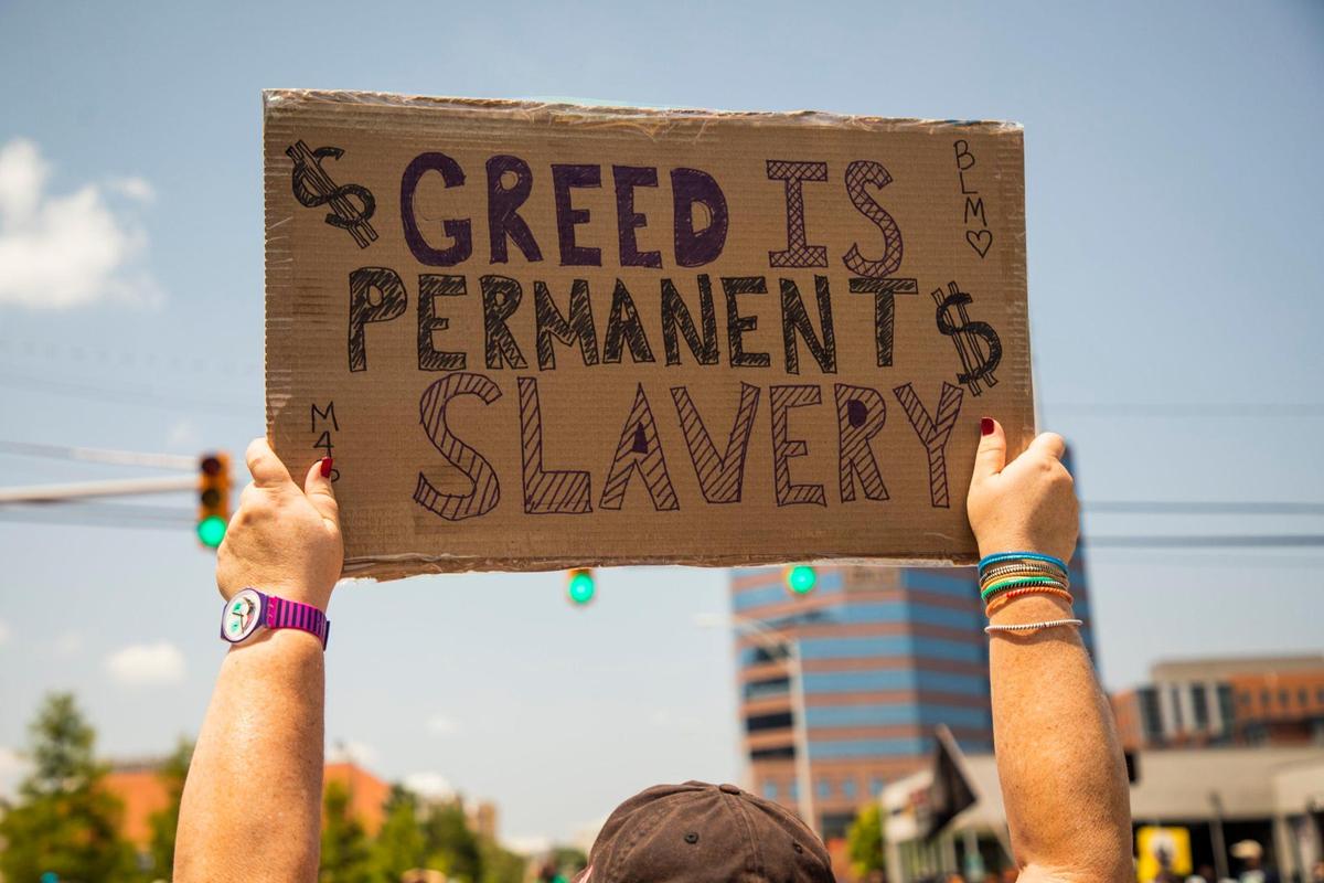 A protester raises their sign while gathered outside McDonaldÕs during a nationwide ÔStrike for Black LivesÕ bringing together low-wage workers deemed essential during the coronavirus pandemic to demand safer working conditions and higher wages in order address poverty and police brutality in marginalized communities, on Monday, July 20, 2020, in Durham, N.C.