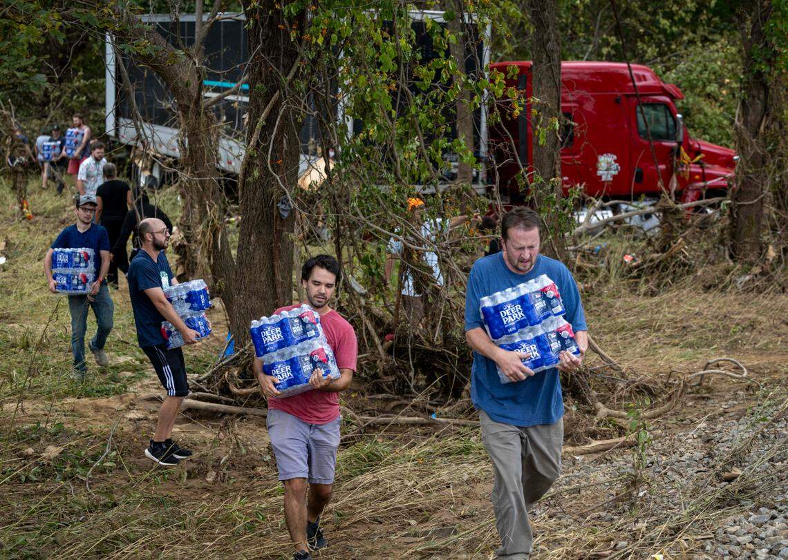 Western North Carolina residents salvage bottled water from a flooded tractor-trailer in Swannanoa on Sunday, Sept. 29, 2024. The remnants of Hurricane Helene caused widespread flooding, downed trees, and power outages in western North Carolina.