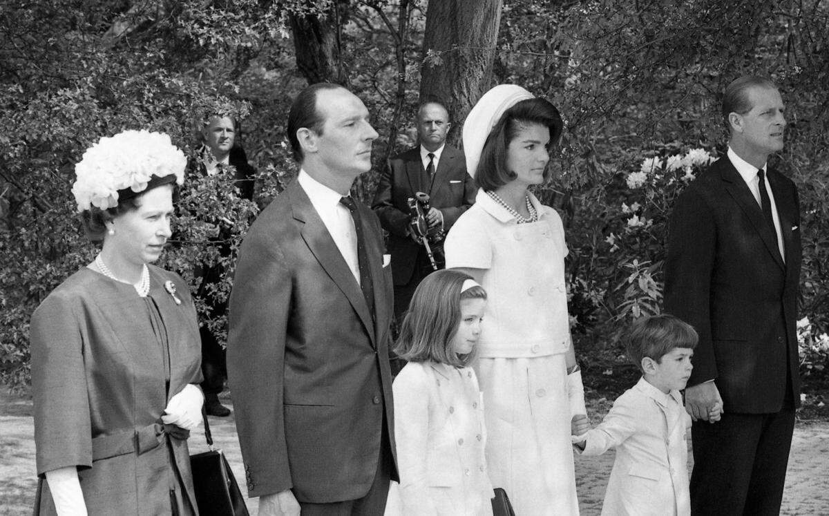 On the hallowed fields of Magna Carta, close to the River Thames at Runneymede, Surrey, on May 14, 1965, Queen Elizabeth II, with Mrs Jackie Kennedy at her side, dedicated Britain’s memorial to the late American President John F. Kennedy. The seven ton Portland stone memorial and the historic ground around became American property, in perpetuity, a gift from the British people. Standing to attention whilst the National Anthem is played are from left to right, Queen Elizabeth II, Lord David Harlech, Chairman of the Trustees, Caroline Kennedy, Mrs Jackie Kennedy, John Kennedy Jr. holding the Duke of Edinburgh’s hand.