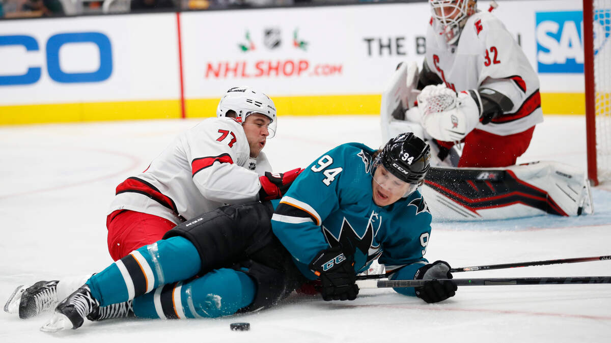 Carolina Hurricanes defenseman Tony DeAngelo (77) collides with San Jose Sharks left wing Alexander Barabanov (94) as they battle for the puck during the first period of an NHL hockey game Monday, Nov. 22, 2021, in San Jose, Calif. (AP Photo/Josie Lepe)