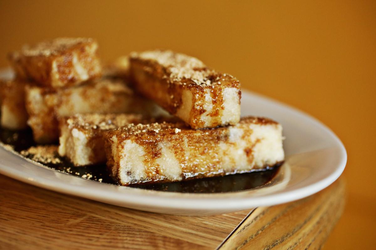 Chengdu 7’s brown sugar and sweet rice buns are rectangular cakes of sticky rice, sitting in a dark puddle of brown sugar caramel, and sprinkled with more brown sugar in granulated form.