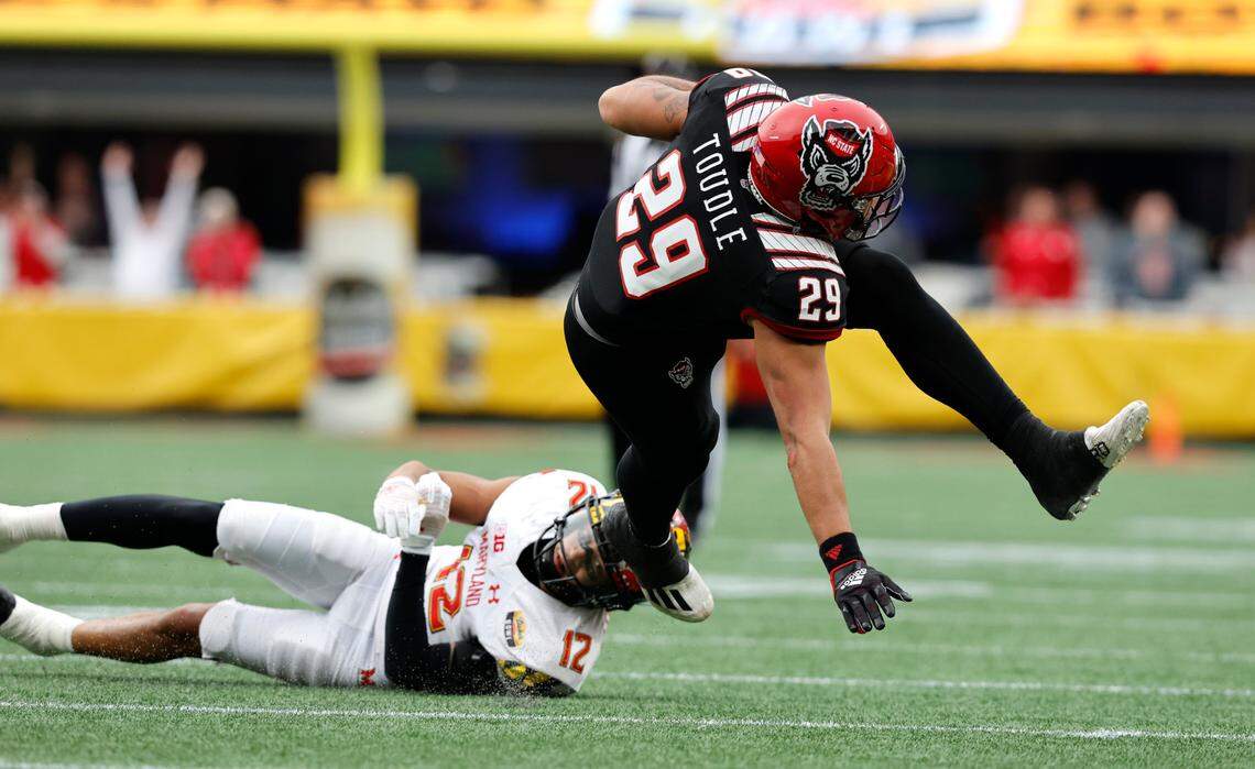 N.C. State’s Christopher Toudle (29) gets tripped up by Maryland defensive back Dante Trader Jr. (12) during the second half of Maryland’s 16-12 victory over N.C. State in the Duke’s Mayo Bowl at Bank of America Stadium in Charlotte, N.C., Friday, Dec. 30, 2022.