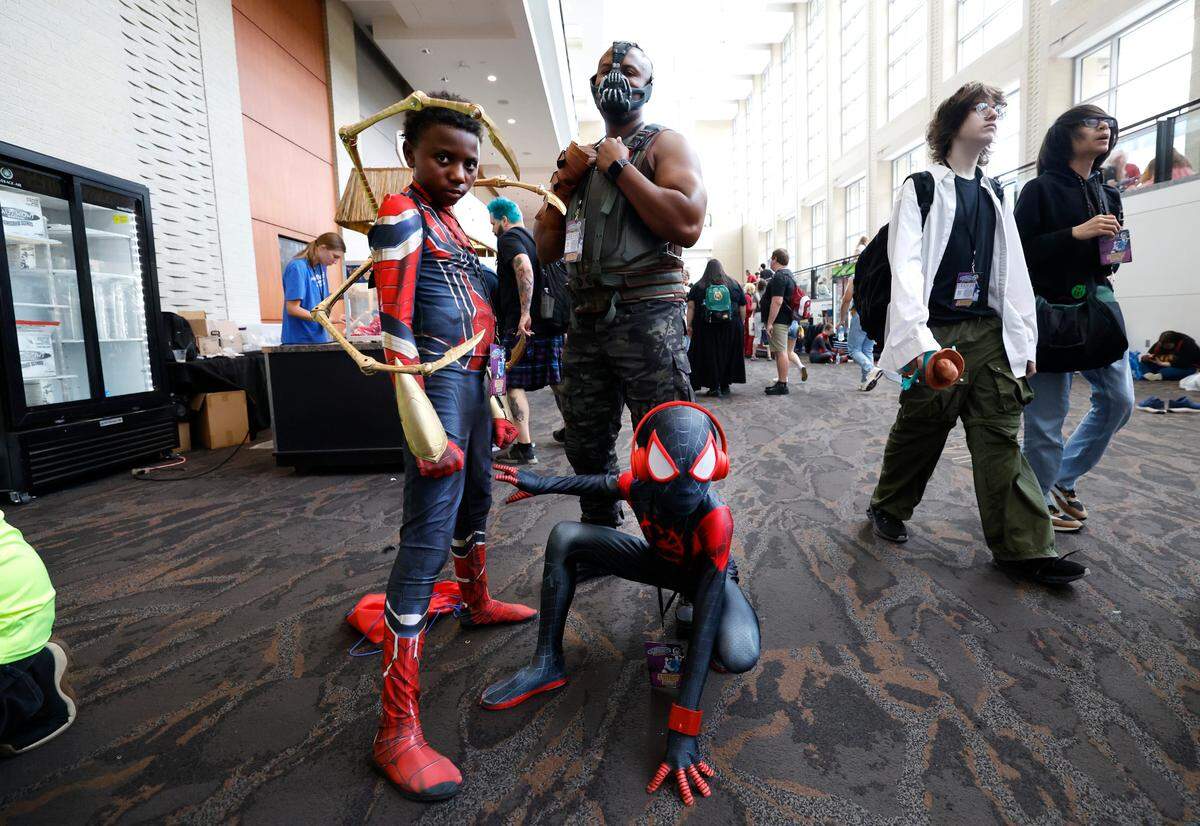 Will Malloy of Clayton and his sons Ayden, 12, and Austin 9, Austin, 9, pose GalaxyCon Raleigh at the Raleigh Convention Center Sunday, July 28, 2024. Malloy is dressed as Bane while Ayden is Iron Spider-Man and Austin is Miles Morales.