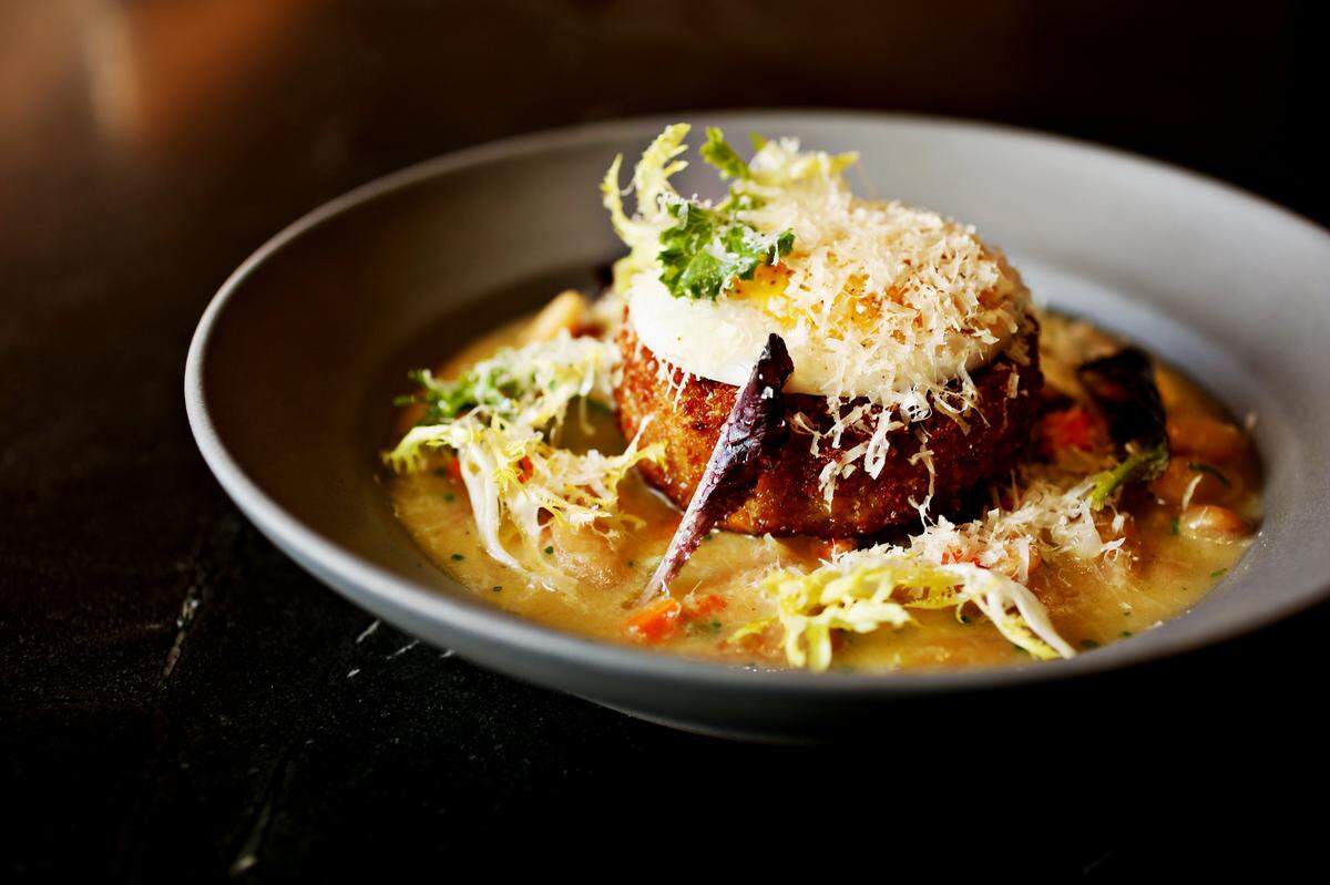 The crispy duck croquette is served over cannellini beans in a garlicky broth that's evocative of a cassoulet, and topped with a poached duck egg at Crawford & Son in Raleigh .