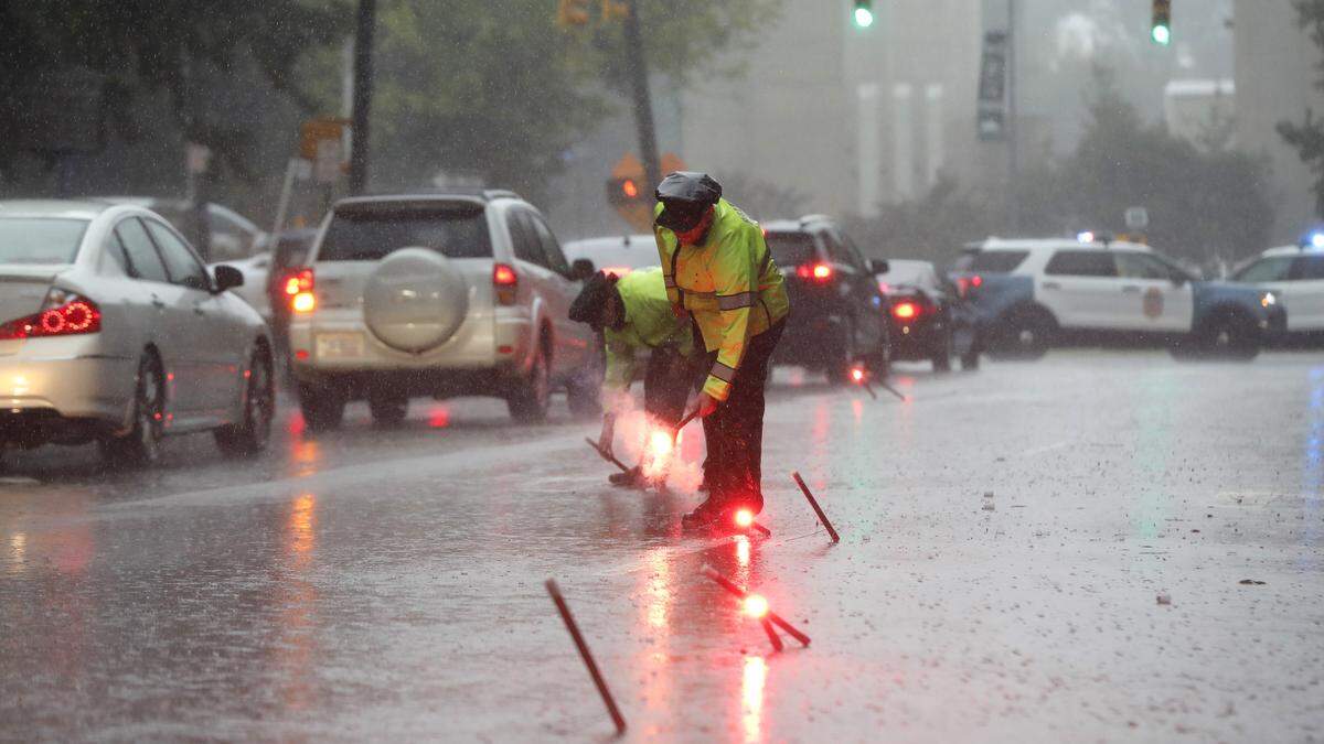 Raleigh police officers A.S. Freese and B.S. Smith set flares to funnel traffic off N. McDowell Street at West Lane St. as rain from Tropical Storm Michael hits downtown Raleigh, Thursday, October 11, 2018.