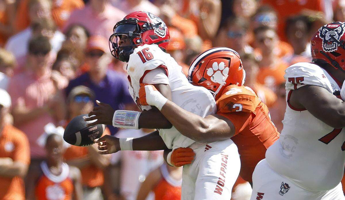 N.C. State quarterback Grayson McCall (2) loses the ball while being sacked by Clemson defensive end T.J. Parker (3) during the first half of N.C. State’s game against Clemson at Memorial Stadium in Clemson, S.C., Saturday, Sept. 21, 2024.