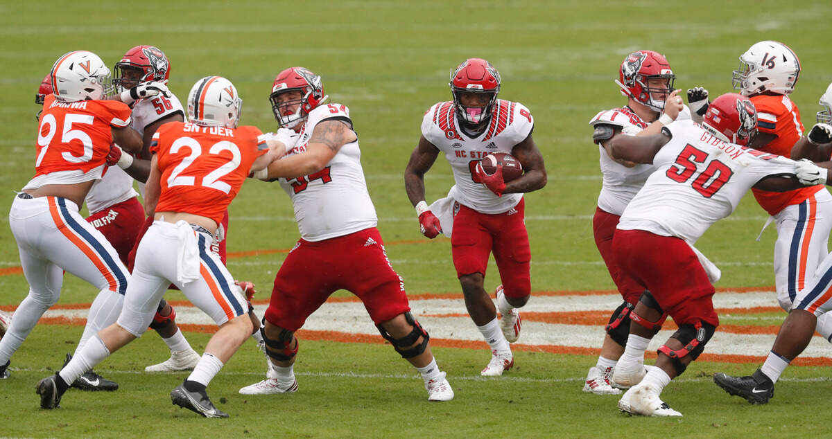 N.C. State’s Ricky Person Jr. (8) runs through the hole opened up by Bryson Speas (56), Dylan McMahon (54), Joe Sculthorpe (71) and Grant Gibson (50) during the first half of N.C. State’s game against Virginia at Scott Stadium in Charlottesville, Va., Saturday, Oct. 10, 2020.