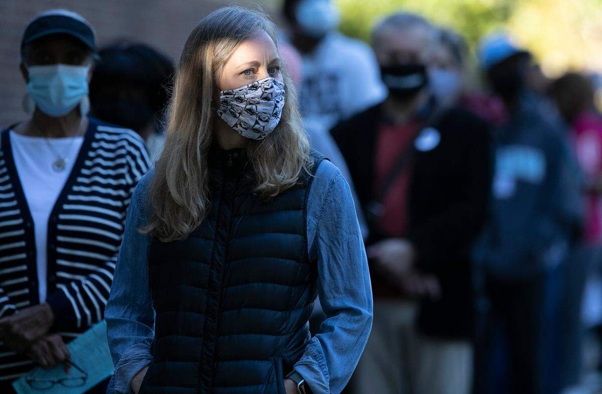 The morning sunshine illuminates Amber Smith Vance as she waits in line to vote with several hundred others at the Roberts Park early voting site on Thursday morning, October 15, 2020 in Raleigh, N.C.