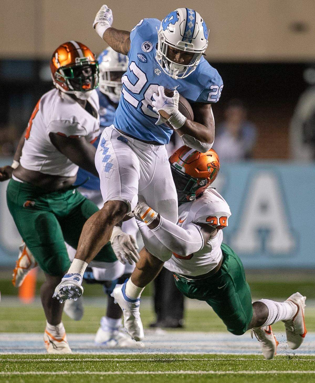 North Carolinas Omarion Hampton (28) picks up 11 yards as he hurdles over Florida A&Ms Johnny Chaney Jr. (28) in the first quarter on Saturday, August 27, 2022 at Kenan Stadium in Chapel Hill, N.C.
