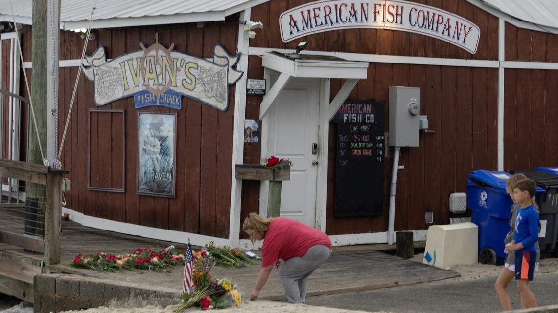 A woman and two children pay their respects at a memorial outside of American Fish Company in Southport, where three people were killed by a gunman shooting from a boat in the Cape Fear River.