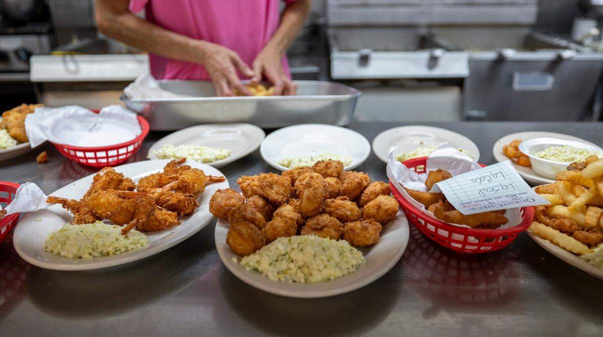 Plates piled high with shrimp, scallops and fish in the kitchen of the Calabash Seafood Hut on Saturday, June 29, 2024 in Calabash, N.C.