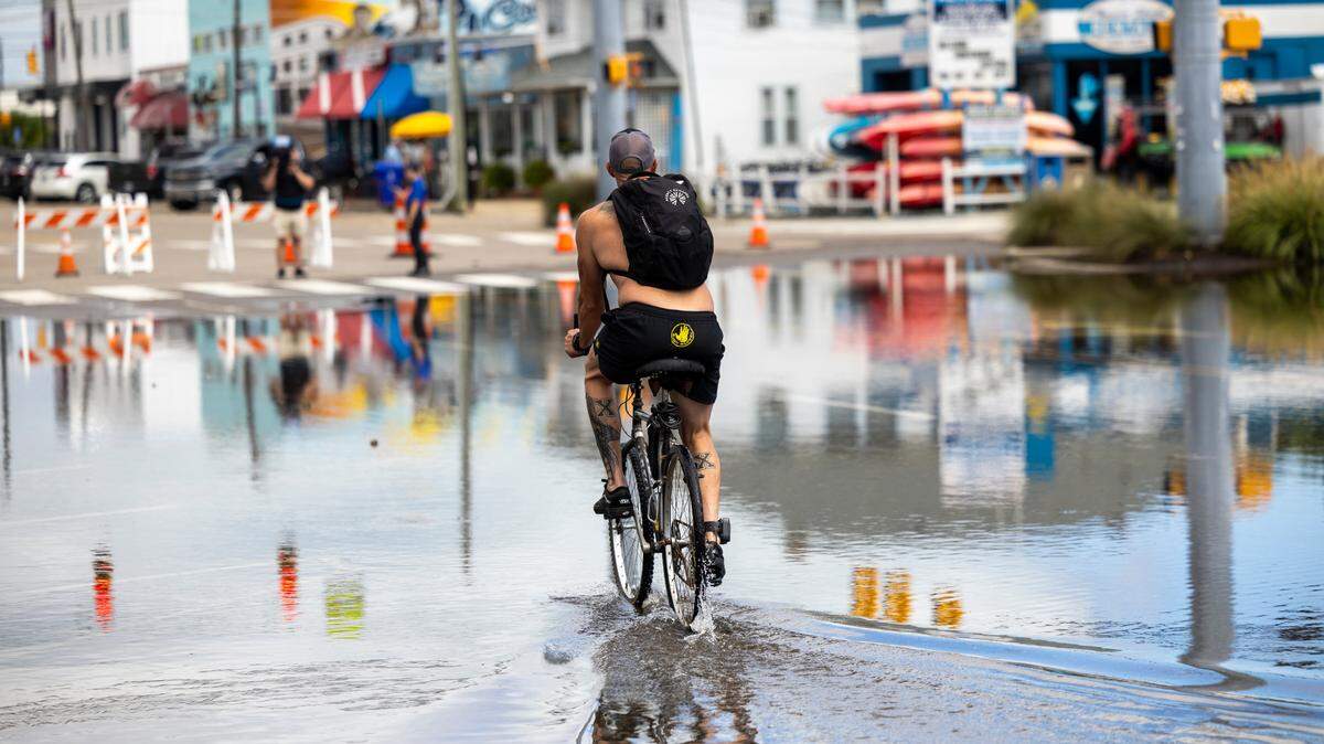 A cyclist pedals through floodwaters as water levels recede in Carolina Beach on Tuesday, Sept. 17, 2024 after an unnamed storm dropped as much as 18 inches of rain in part of southeastern North Carolina over a 72-hour period. Flood Levels in Carolina Beach rivaled that of Hurricane Floyd in 1999.