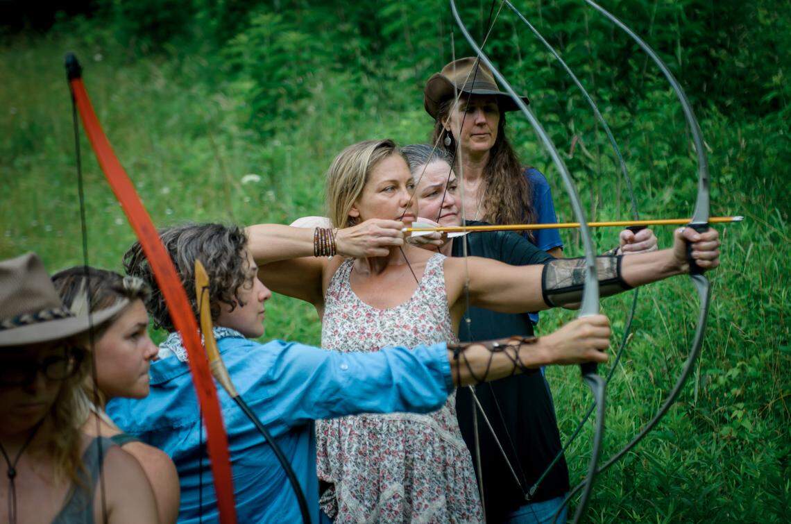 Women at the rewilding weekend at Wild Abundance take an archery lesson.