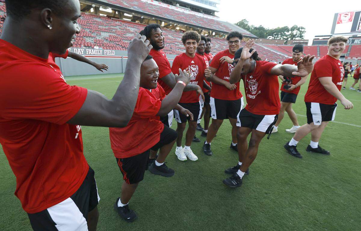 Jason Frederick celebrates with N.C. State football players after scoring a touchdown during the Wolfpack’s Victory Day at Carter-Finley Stadium Saturday, Aug. 16, 2025. N.C. State hosted its annual event with Gigi’s Playhouse to give individuals with disabilities a chance to experience football.