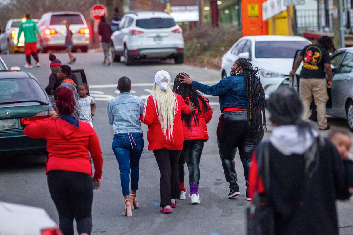 Mourners console each other after a balloon release Thursday, Dec. 16, 2021 in Durham at the site of a Monday morning shooting that left two teenagers dead and four other children injured.