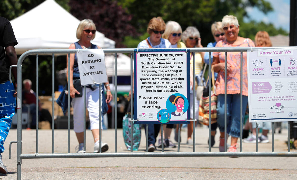 The sign for Executive Order 147 from June 2020, requiring face masks in public when social distancing is not possible, is still displayed at The Raleigh Market at the N.C. State Fairgrounds in Raleigh, N.C., Saturday, May 15, 2021. Gov. Roy Cooper said Friday that it’s now safe for people to move around in public without wearing a mask.