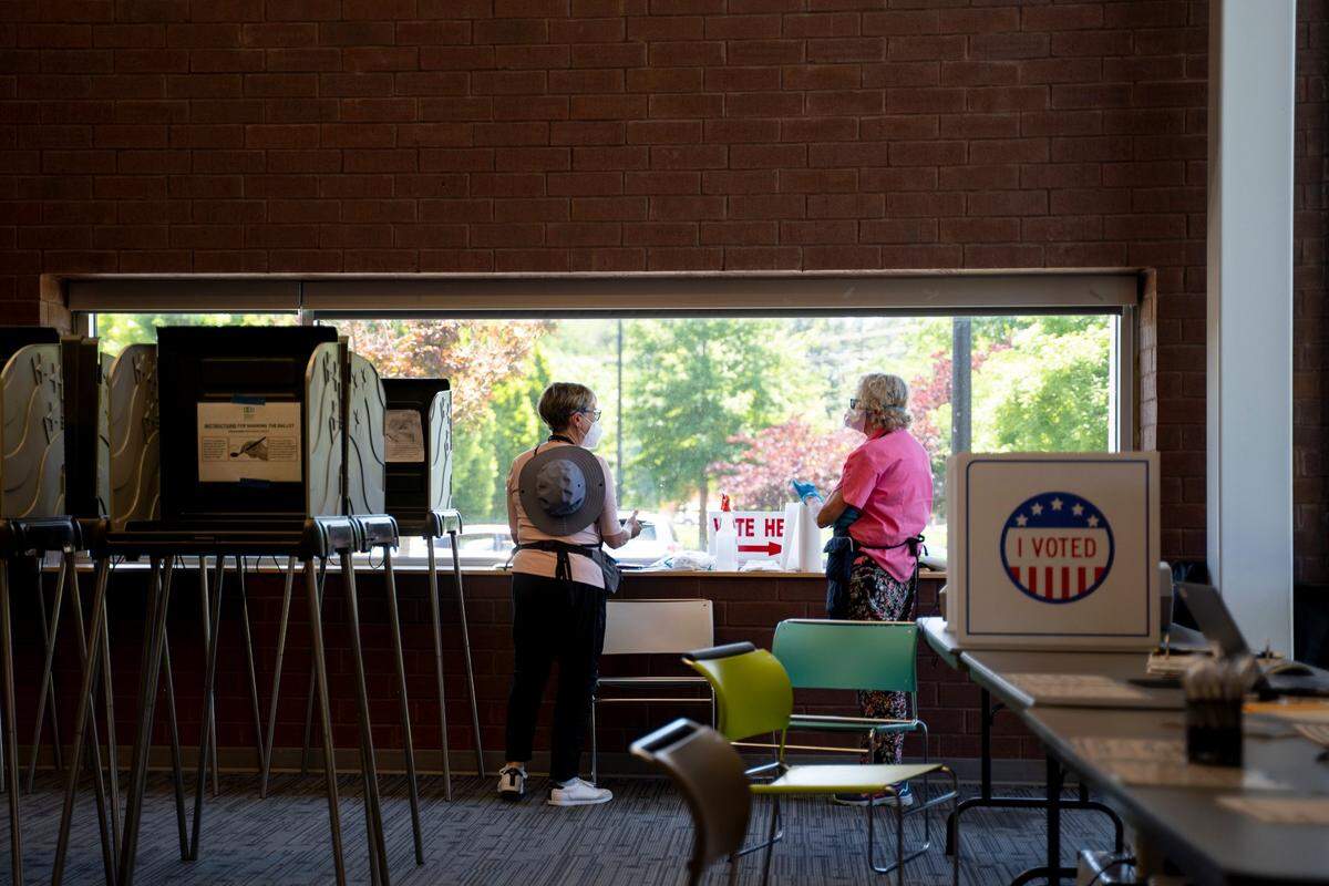 A volunteer and voter chat inside the polling site at South Regional Durham County Library in Durham, N.C. on Tuesday, May 17, 2022.
