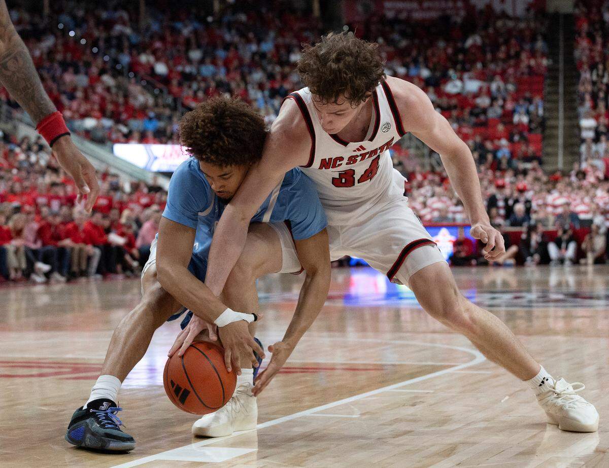 North Carolina’s Seth Trimble and N.C. State’s Ben Middlebrooks scramble for a loose ball during the first half of the Wolfpack’s game at Lenovo Center on Saturday, Jan. 11, 2025, in Raleigh, N.C.