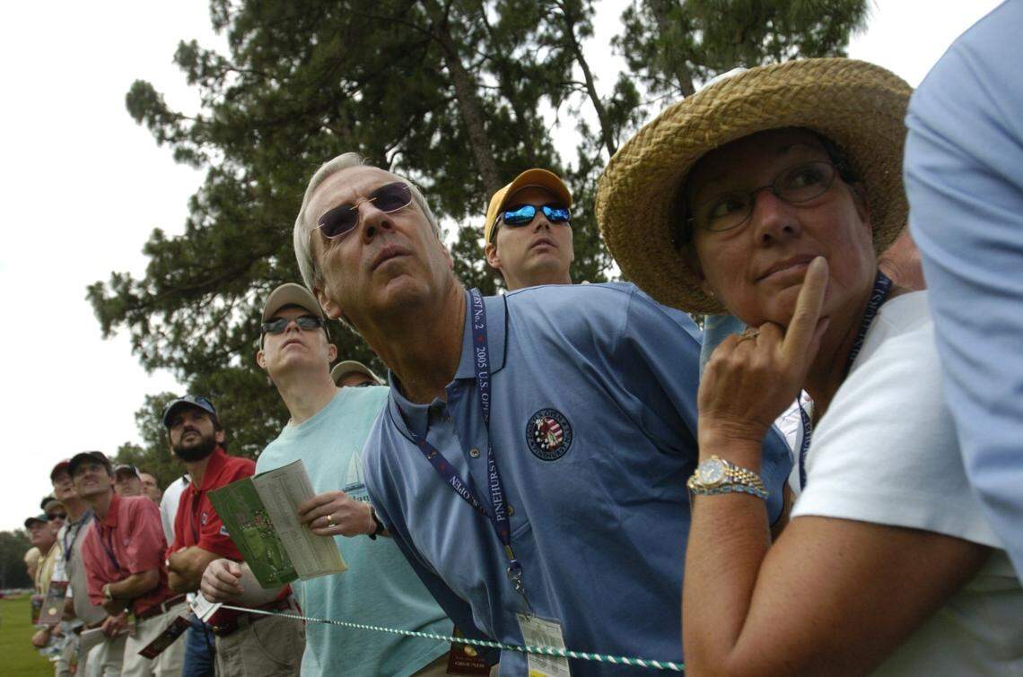 UNC basketball Coach Roy Williams and his wife Wanda, right, lean out to watch Davis Love III’s fairway shot on 16 during the second round of the US Open.
