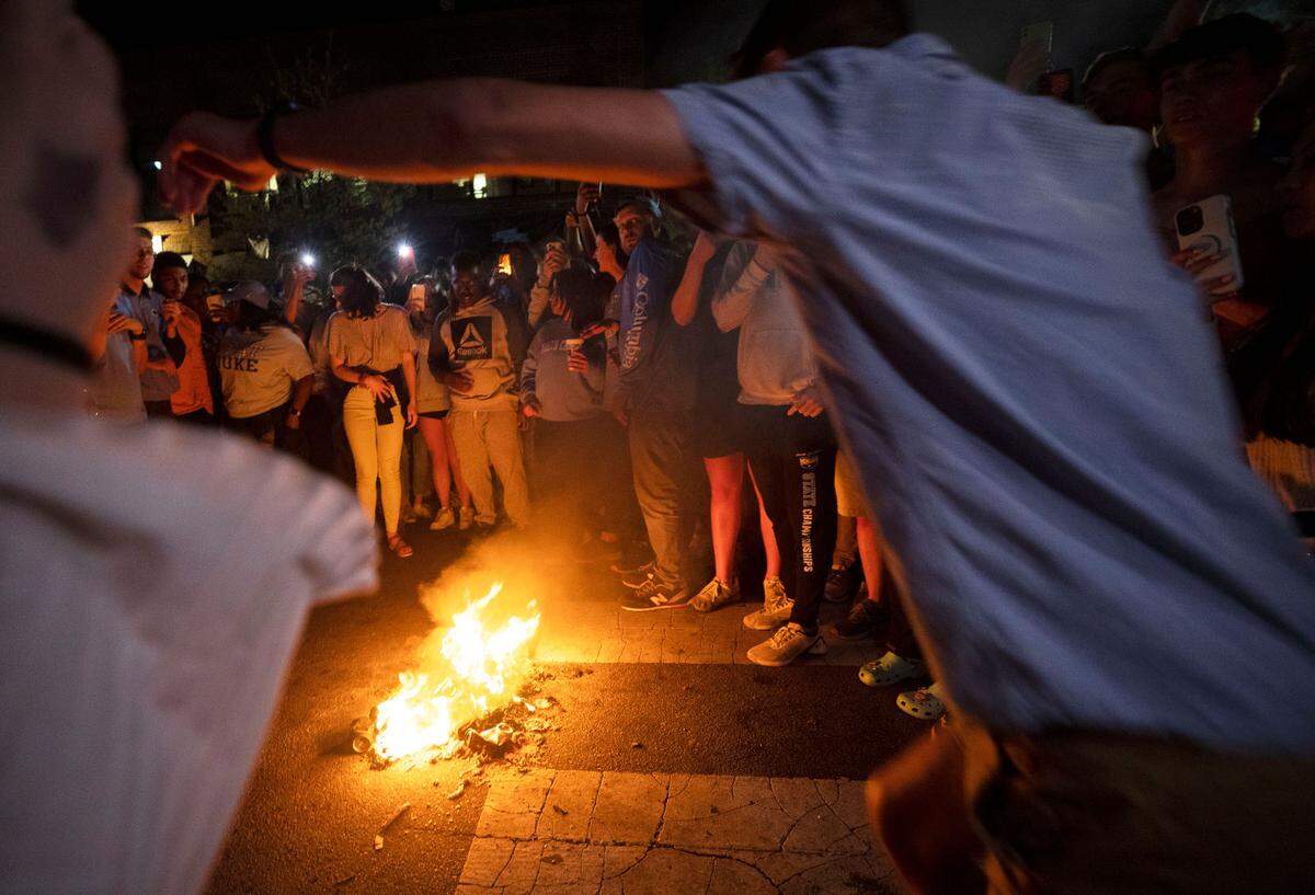 A Tar Heel fan prepares to jump over a fire on Franklin Street in Chapel Hill, N.C. as fans celebrate UNC’s historic Final Four win against Duke on Saturday, April 2, 2022.