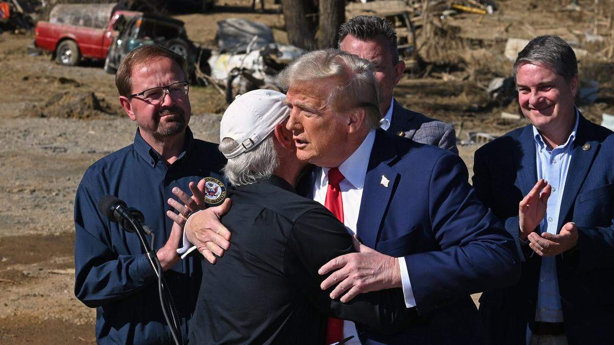 Former President Donald J. Trump, right, is hugged by a local Swannanoa, NC business owner, left, who led Monday’s group in prayer during Trump’s stop in the area to see the damage caused by Hurricane Helene. 