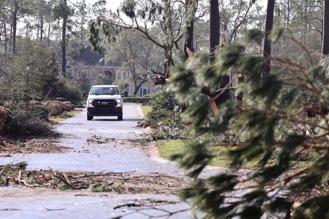 A truck makes its way down a debris-strewn roadway in Brunswick County, N.C. Tuesday morning Feb. 16, 2021 after a tornado ripped through the area killing three and injuring at least 10.