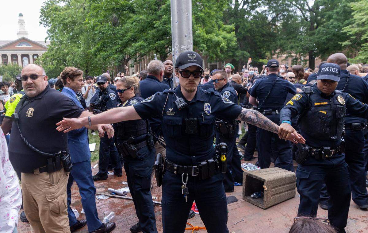 Interim Chancellor Lee Roberts and police officers work to rehang an American flag after it was brought down by demonstrators and replaced with a Palestinian flag Tuesday, April 30, 2024 at UNC-Chapel Hill. About 1000 pro-Palestinian demonstrators rallied after a “Gaza solidarity encampment” was removed by police early Tuesday morning.