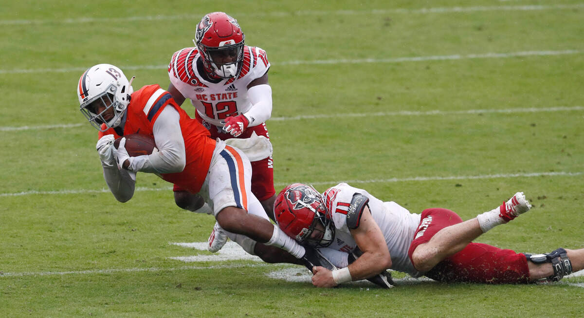 N.C. State linebacker Payton Wilson (11) tackles Virginia wide receiver Terrell Jana (13) as cornerback Devan Boykin (12) comes in to help during the second half of N.C. State’s 38-21 victory over Virginia at Scott Stadium in Charlottesville, Va., Saturday, Oct. 10, 2020.