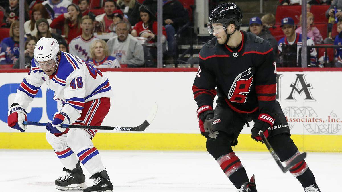 New York Rangers left wing Brendan Lemieux (48) passes the puck while Carolina Hurricanes defenseman Brett Pesce, right, defends during the first period of an NHL hockey game in Raleigh, N.C., Friday, Feb. 21, 2020. (AP Photo/Gerry Broome)