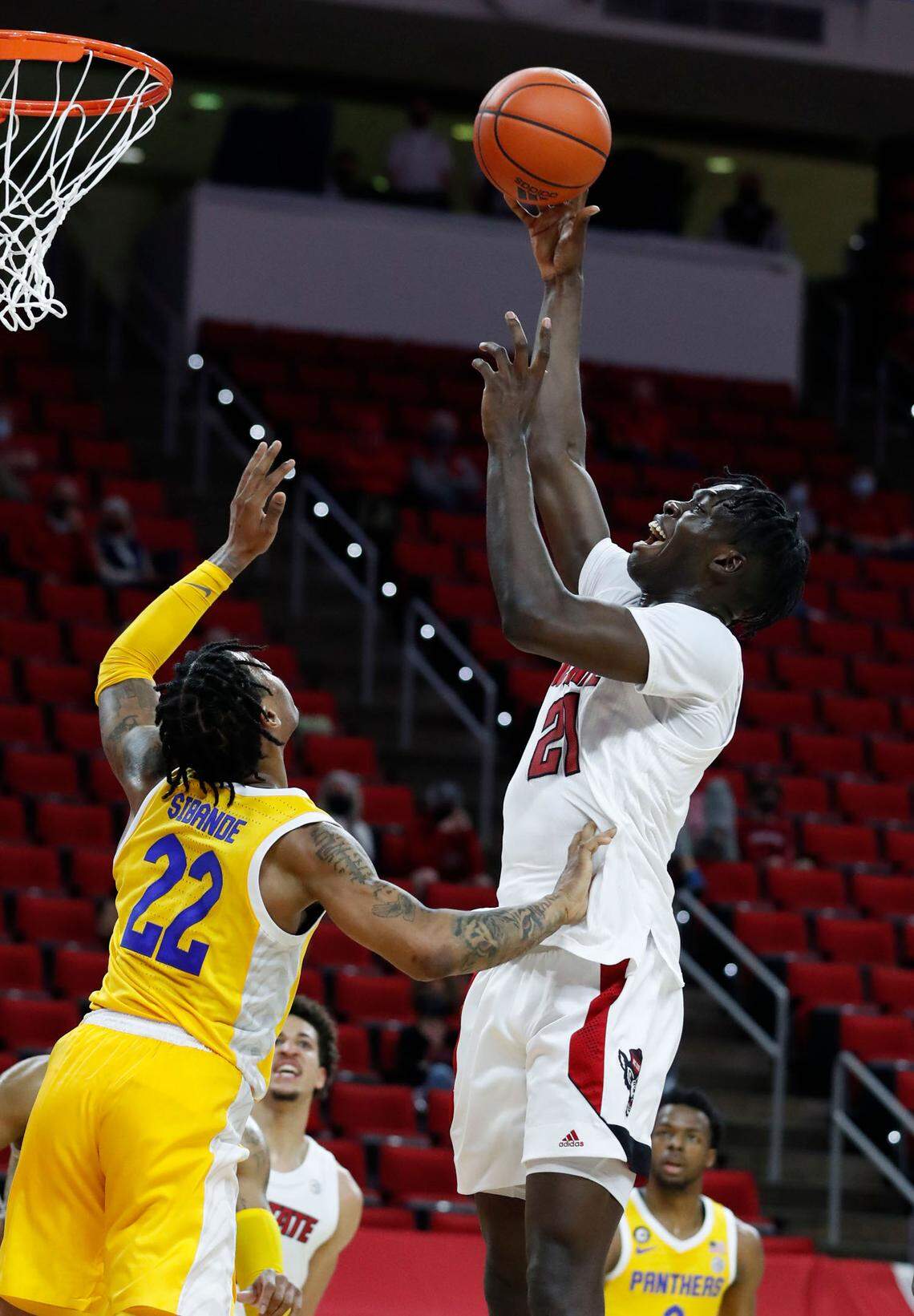 N.C. State’s Ebenezer Dowuona (21) shoots as Pittsburgh’s Nike Sibande (22) defends during the first half of N.C. State’s game against Pittsburgh at PNC Arena in Raleigh, N.C., Sunday, February 28, 2021.