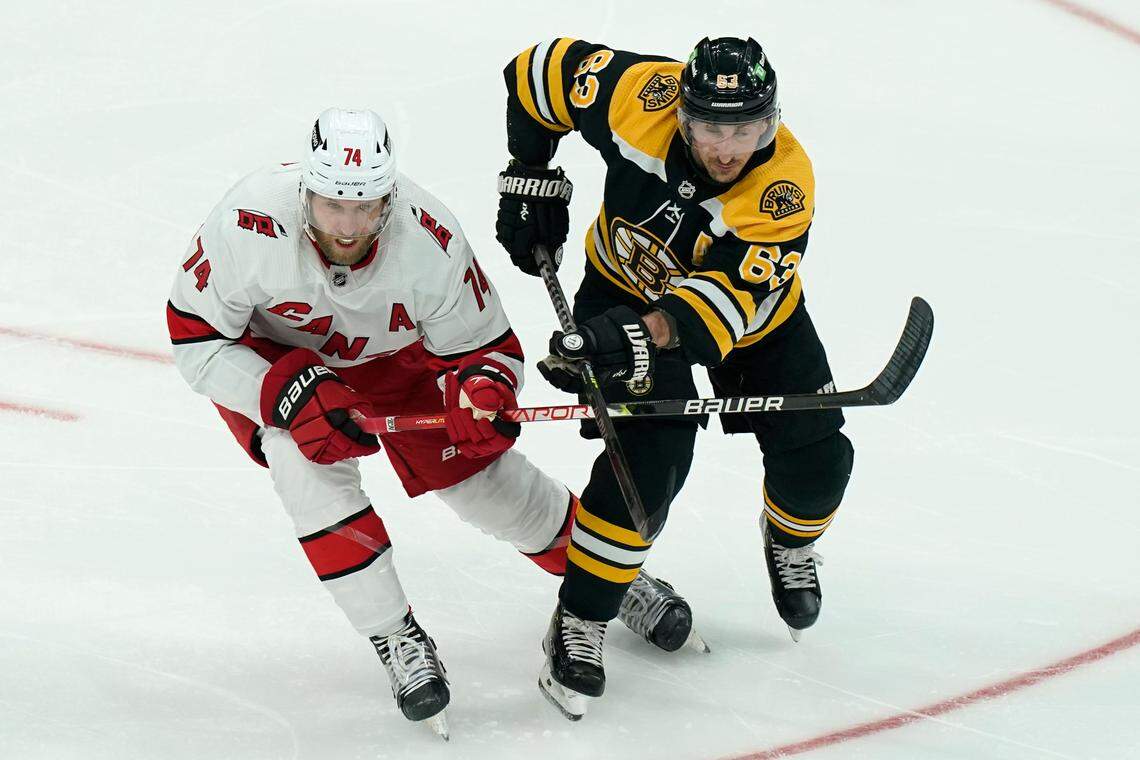 Carolina Hurricanes’ Jaccob Slavin (74) and Boston Bruins’ Brad Marchand (63) pursue the puck in the second period of Game 4 of an NHL hockey Stanley Cup first-round playoff series, Sunday, May 8, 2022, in Boston. The Bruins won 5-2. (AP Photo/Steven Senne)