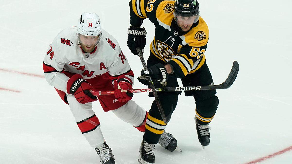 Carolina Hurricanes’ Jaccob Slavin (74) and Boston Bruins’ Brad Marchand (63) pursue the puck in the second period of Game 4 of an NHL hockey Stanley Cup first-round playoff series, Sunday, May 8, 2022, in Boston. The Bruins won 5-2. (AP Photo/Steven Senne)