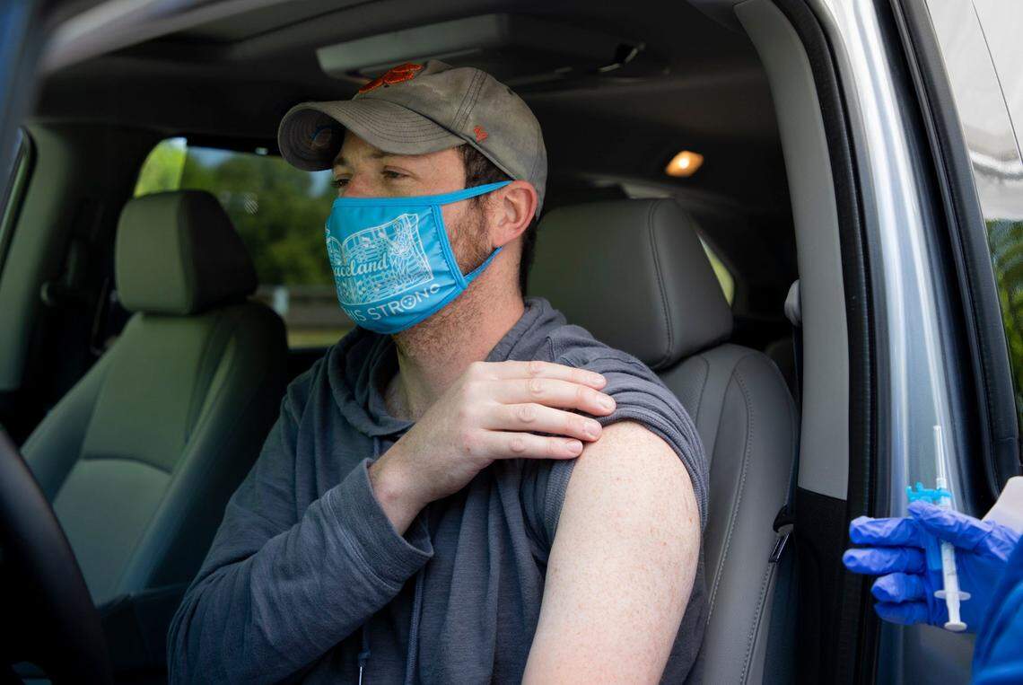 Joe Jannik, left, lifts his sleeve to receive his first dose of the Moderna COVID-19 vaccine from Elsa Pantoja Garcia at a temporary free drive-thru vaccine site, that is normally a free drive-thru testing site, at the Wendell Community Center, on Thursday, Apr. 22, 2021, in Wendell, N.C.