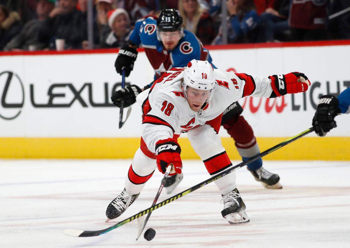 Carolina Hurricanes center Ryan Dzingel, front, reaches out for the puck as Colorado Avalanche right wing Valeri Nichushkin pursues during the third period of an NHL hockey game Thursday, Dec. 19, 2019, in Denver. Carolina won 3-1. (AP Photo/David Zalubowski)